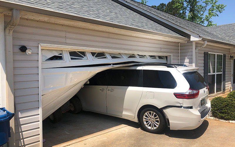 Garage door bent and pushed out of its track after being hit by a vehicle